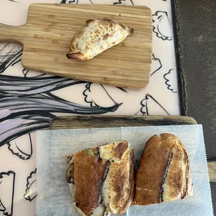 two sandwiches on cutting boards on a table