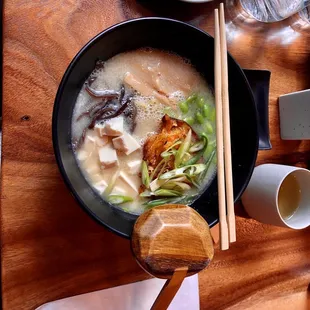 a bowl of ramen and chopsticks on a wooden table