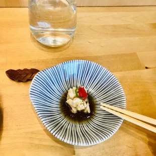 a plate of food with chopsticks and a glass of water