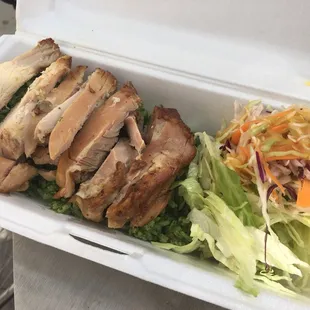 a chicken sandwich and salad in a styrofoam container