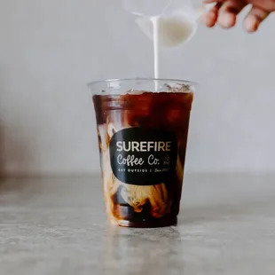 a person pouring milk into a cup