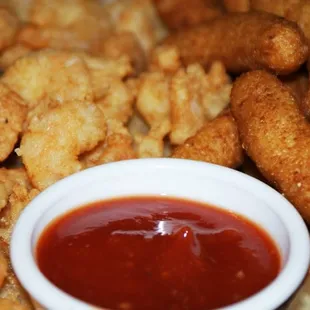 a bowl of ketchup next to a pile of fried tater tots