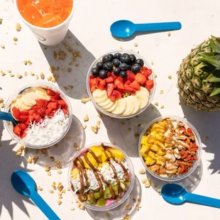a variety of bowls of fruit and yogurt