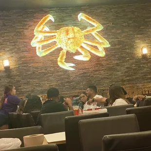 Inside of the restaurant with a light up crab sign on the wall.
