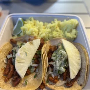 two tacos and rice on a tray