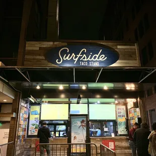 people standing outside of a restaurant at night