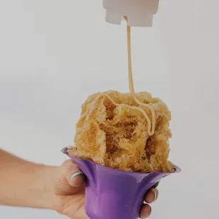 a person's hand holding a cup of food