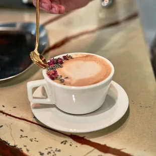 a hand holding a spoon over a cup of coffee