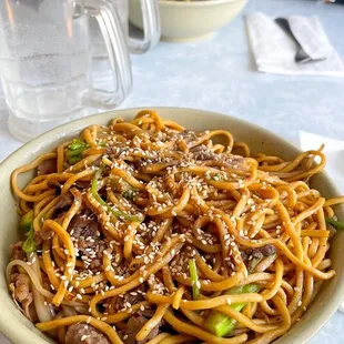 a bowl of noodles and a glass of water