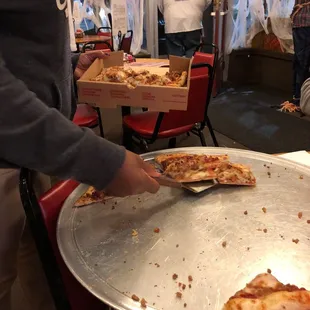 a person grabbing a slice of pizza