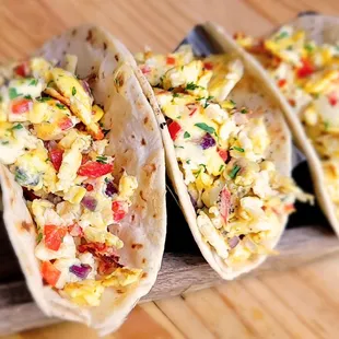 three breakfast tacos on a cutting board