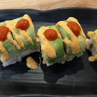three pieces of sushi on a black plate