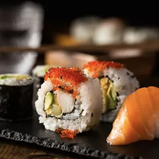 a variety of sushi on a black plate