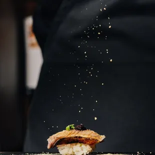 a person sprinkling salt on a piece of food