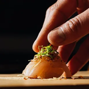 a person placing a piece of sushi on a cutting board