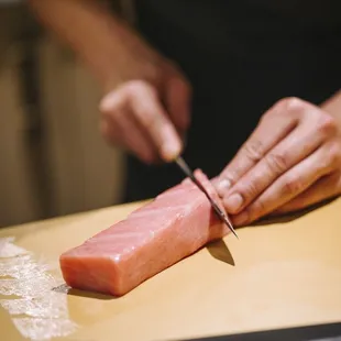 a person cutting a piece of sushi