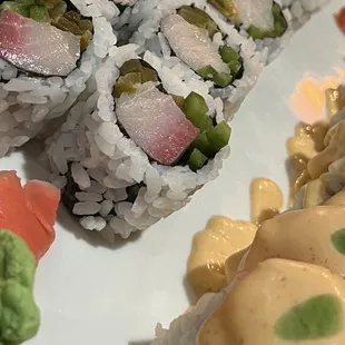a plate of sushi with sauce and vegetables