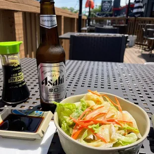 a bowl of salad and a bottle of beer