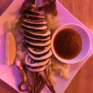 a plate of octopus legs and a bowl of sauce