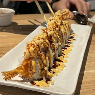 a person holding chopsticks over a sushi
