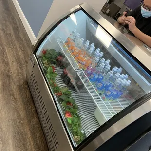 a man wearing a face mask in front of a refrigerated display case