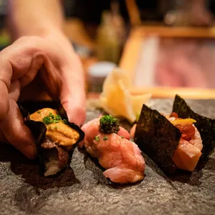 a close up of a person&apos;s hand grabbing a piece of sushi