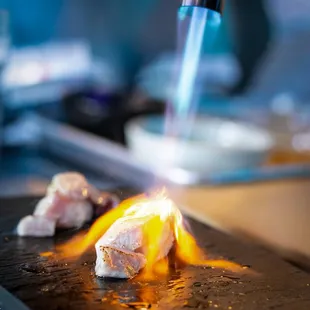 a close up of a piece of meat being made with a flame