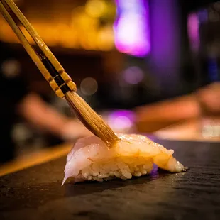 a sushi being dipped with chopsticks