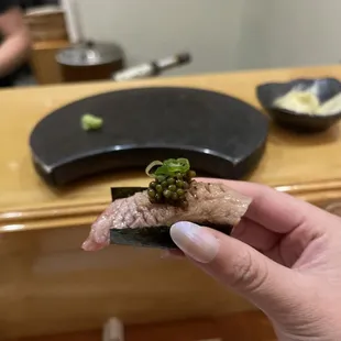 a hand holding a piece of sushi