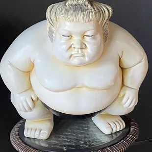 a statue of a sumo sitting on a stool