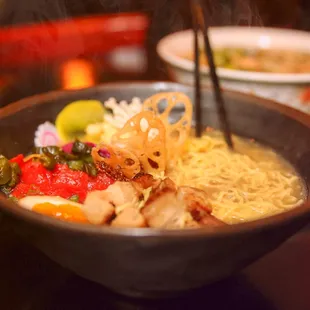 Tonkatsu Ramen in a creamy pork broth, served with marinated pork belly, soy marinated egg, black chili paste, red curry pickles, and more!