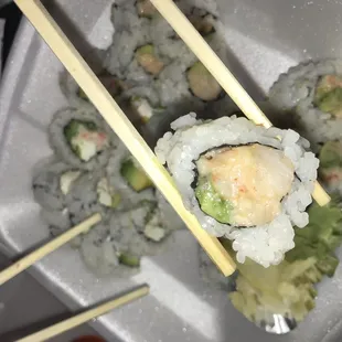 a close up of a plate of sushi with chopsticks