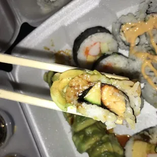a person holding chopsticks over a plate of sushi