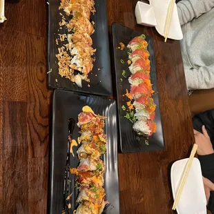 a variety of sushi dishes on black plates