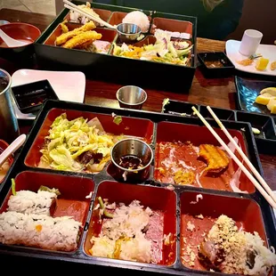 a woman sitting at a table with a tray of food and chopsticks