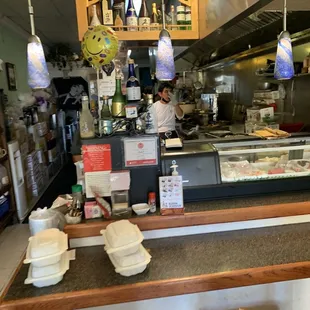 a sushi restaurant counter with a man in the background