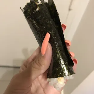 a hand holding a piece of sushi