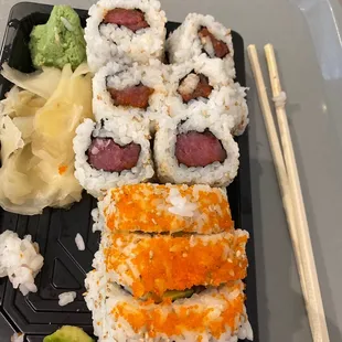 a tray of sushi and chopsticks