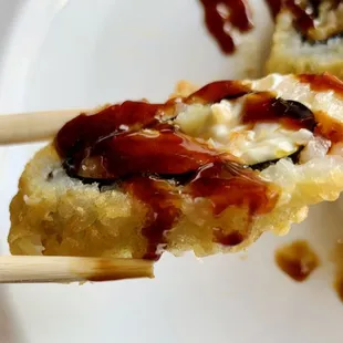 a piece of sushi on a plate with chopsticks