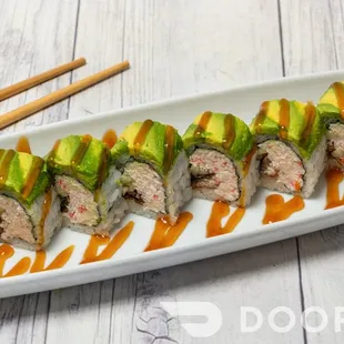 a plate of sushi rolls with avocado sauce and chopsticks