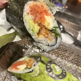  a hand holding a piece of sushi