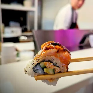 a sushi being held by a pair of chopsticks