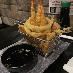 a basket of onion rings and a bowl of dipping sauce