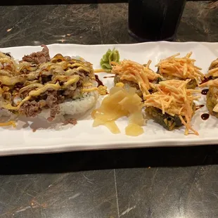 a plate of sushi with meat and vegetables