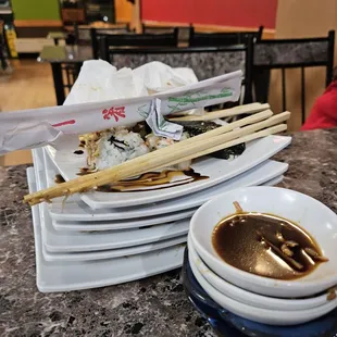 a stack of plates with chopsticks and sauce