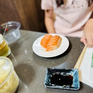 a person sitting at a table with a plate of sushi