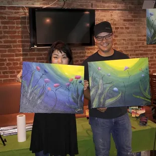 a man and a woman holding paintings