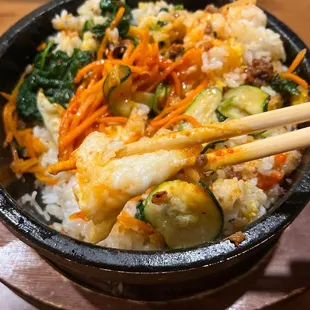 a bowl of rice and vegetables with chopsticks