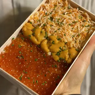 a person holding a box of sushi