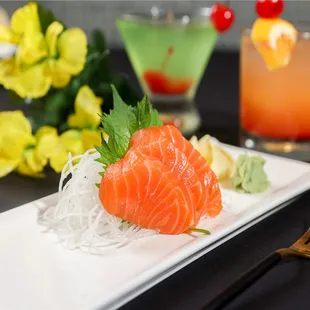 a plate of sushi with a cocktail in the background